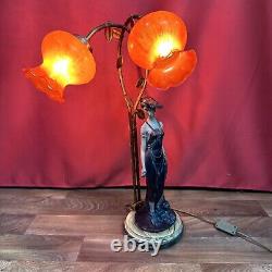 Lampe de table à deux lumières représentant une figure féminine dans le style Art Déco / Nouveau avec des abat-jours floraux rouges.