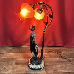 Lampe de table à deux lumières représentant une figure féminine dans le style Art Déco / Nouveau avec des abat-jours floraux rouges.